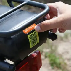 Hand plaatst sticker met QR-code op e-bike accu. Dit is een gestolen fiets register om diefstal te voorkomen.