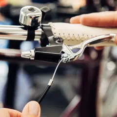 Hand replacing a bicycle's remkabel. Close-up of the brake lever and cable connection.
