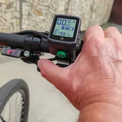Hand op stuur van een elektrische fiets zonder trappen. Het display toont 00.0 km/u en 198.1 km.