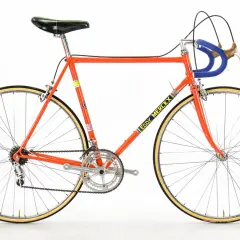 Klassieke racefiets in fel oranje, met "Eddy Merckx" op de buis. Een iconisch stukje fietsgeschiedenis.