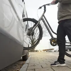 Man met fiets bij auto. Een diefstal preventie chip op de fiets zorgt voor extra veiligheid.