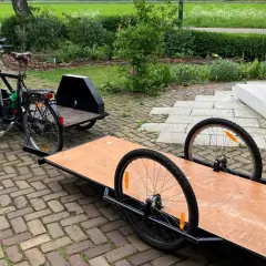 Een fiets met een bakfiets-achtige constructie en een aanhanger, klaar om een zijspan fiets te maken.