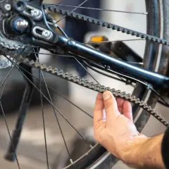 Hand controleert de riem van een fiets, mogelijk ter voorbereiding op het vervangen van de riem fiets.