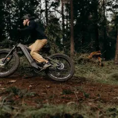 Man op een elektrische fiets in het bos, de fiets trapt zwaar door het ruige terrein.