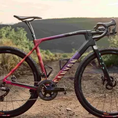 Een kleurrijke Canyon fiets, ideaal voor cyclocross vs gravel bike avonturen, staat in een droog, heuvelachtig landschap.