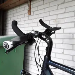 Stuur van een fiets met handvatten en een bel. Geen mountainbike bar ends te zien, wel een groene bak ernaast.