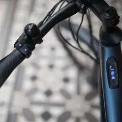 Stuur van een blauwe elektrische fiets met een display dat aangeeft dat de elektrische fiets slaat op hol. De batterij is vol.