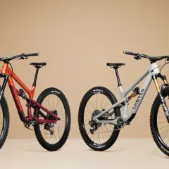 Twee mountainbikes, één oranje/rood en één grijs, met duidelijke wielmaat en Maxxis banden.