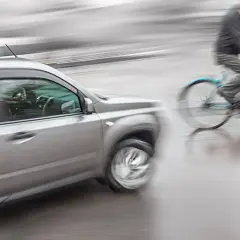 Een auto en fietser in beweging, mogelijk een situatie die leidt tot schadevergoeding fietsongeval.
