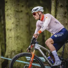 Een Nederlandse wielrenner in actie in het bos, met de Nederlandse Loterij op zijn shirt.
