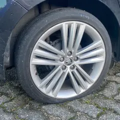 Een lekke band op de racefiets van de auto. De band is plat en de velg rust op de stenen ondergrond.