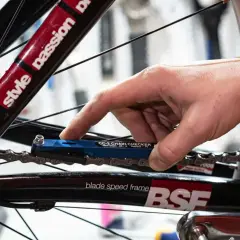 Hand gebruikt een blauwe kettingmeter om te controleren of het tandwiel van de fiets vervangen moet worden.