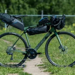 Groene Merida racefiets met bikepacking tassen, klaar voor een avontuurlijke tocht.