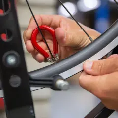 Met een rode spaaksleutel wordt een fietswiel gericht. Een hand draait aan de nippel om het wiel weer perfect rond te maken.