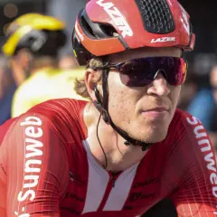 Een wielrenner in rood Sunweb-tenue, met helm en zonnebril, klaar voor de strijd. Bekende wielrenners zoals hij maken indruk.