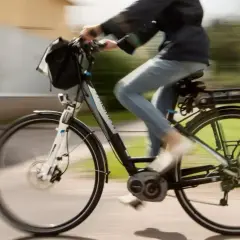 Een persoon op een elektrische fiets, die met gemak 30 km/u bereikt, fietst langs een groen park.