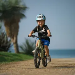 Vrolijk meisje op een fiets met een cube framemaat, genietend van de zon en de zee.