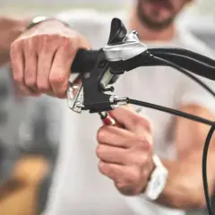 Man stelt de terugtraprem af met een sleutel aan het stuur van een fiets.