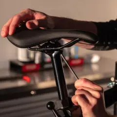 Handen die een fietszadel vervangen met een inbussleutel.