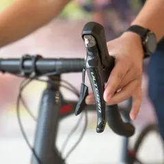 Hand op het schakelen van een racefiets, met de Ultegra-aanduiding zichtbaar op de remhendel.