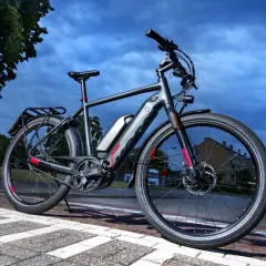 Grijze speed pedelec met bagagedrager en accu, klaar voor een rit. Het kenteken is niet zichtbaar, maar de fiets is wel voorzien van alle benodigde onderdelen.