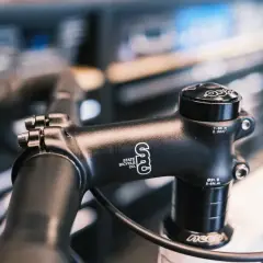 Zwarte fietsstuurpen, merk State Bicycle Co., met spacers om de stuurpen te verhogen voor een comfortabelere fietshouding.