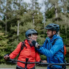 Een stel op mountainbikes, met fietshelm verplicht in Frankrijk, geniet van een bosrit.