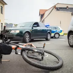 Een fiets ligt op straat na een aanrijding fiets met fiets. Politieauto's zijn ter plaatse.
