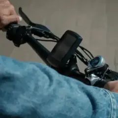 Handen aan het stuur van een elektrische fiets, klaar voor een rit. De aansluiting van de accu is niet zichtbaar, maar de fiets is klaar voor gebruik.