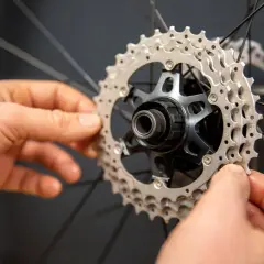 Handen monteren een nieuwe cassette op een fietswiel. Het vervangen van de cassette is een klus die precisie vereist.