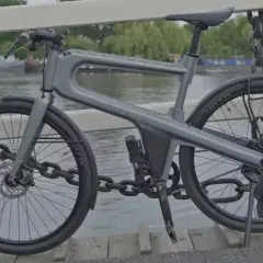 Moderne, hippe stadsfiets met een uniek frame, geparkeerd op een brug met uitzicht op boten.