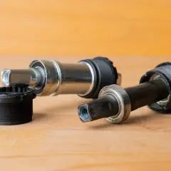 Twee fiets trapassen, een zilverkleurige en een zwarte, liggen klaar voor vervanging.