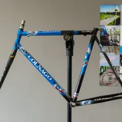 Blauw met witte en rode accenten, een Colnago racefiets frame op een standaard, klaar voor de afmontage.