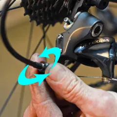 Hand probeert de kabel van de derailleur te bevestigen, maar het derailleur afstellen lukt niet.