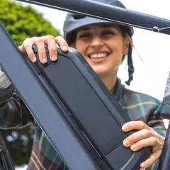 Vrolijke vrouw met helm bevestigt de accu van haar e-bike. Goed accu onderhoud zorgt voor zorgeloze fietstochten.