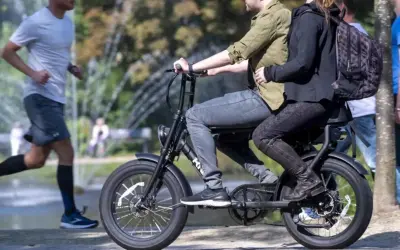 Een stel rijdt op een fatbike, terwijl een hardloper ernaast rent. Nadelen fatbike: minder beweging, meer overlast.
