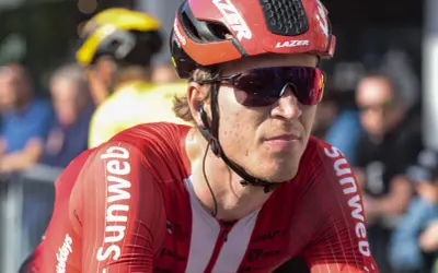 Een wielrenner in rood Sunweb-tenue, met helm en zonnebril, klaar voor de strijd. Bekende wielrenners zoals hij maken indruk.