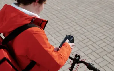 Bezorgbezorger in oranje jas checkt zijn telefoon op de fiets, hopelijk geen boete telefoon fiets!
