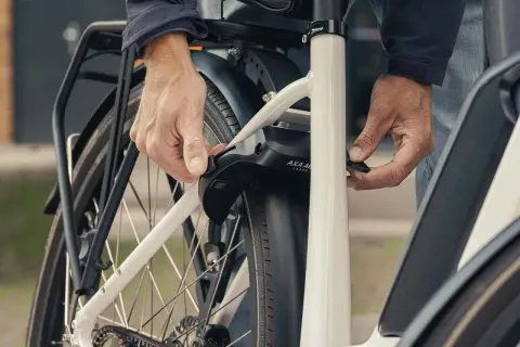 Een persoon bevestigt een ringslot aan een fiets. Dit type slot, wat is een ringslot, beschermt tegen diefstal door het achterwiel te blokkeren.