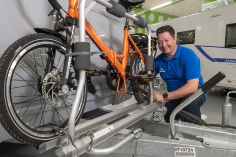 Man toont fietsendrager voor caravan, ideaal om een elektrische fiets veilig te vervoeren.