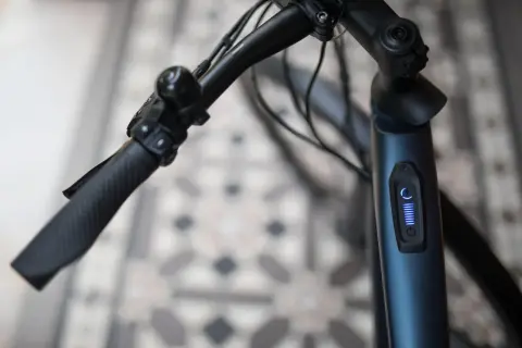 Stuur van een blauwe elektrische fiets met een display dat aangeeft dat de elektrische fiets slaat op hol. De batterij is vol.