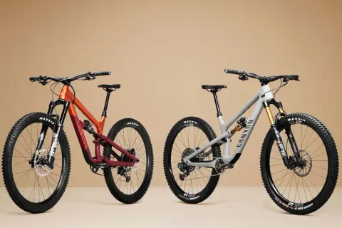 Twee mountainbikes, één oranje/rood en één grijs, met duidelijke wielmaat en Maxxis banden.