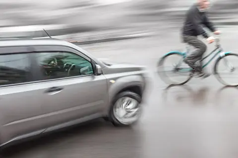 Een auto en fietser in beweging, mogelijk een situatie die leidt tot schadevergoeding fietsongeval.