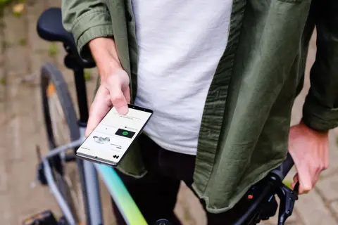 Man op fiets houdt smartphone vast, toont app voor communiceren tijdens fietsen.