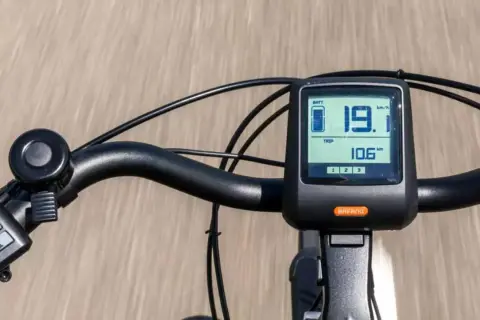 Close-up of an e-bike handlebar with a digital display showing speed and battery level.