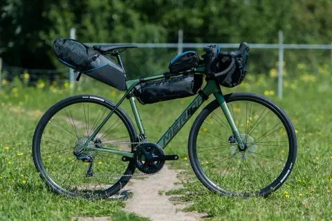 Groene Merida racefiets met bikepacking tassen, klaar voor een avontuurlijke tocht.