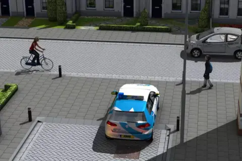 Een fietser van rechts nadert een kruispunt. Een ANWB-auto staat stil, een grijze auto rijdt door.