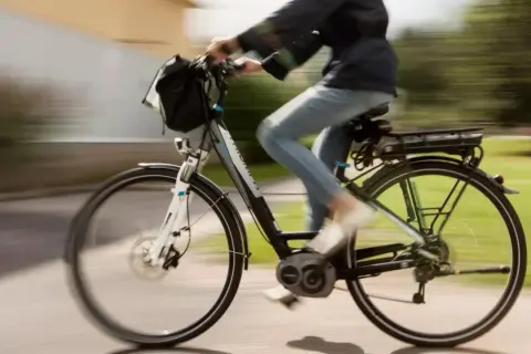 Een persoon op een elektrische fiets, die met gemak 30 km/u bereikt, fietst langs een groen park.