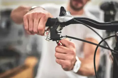 Man stelt de terugtraprem af met een sleutel aan het stuur van een fiets.
