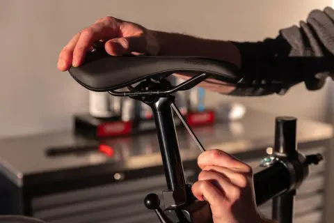 Handen die een fietszadel vervangen met een inbussleutel.